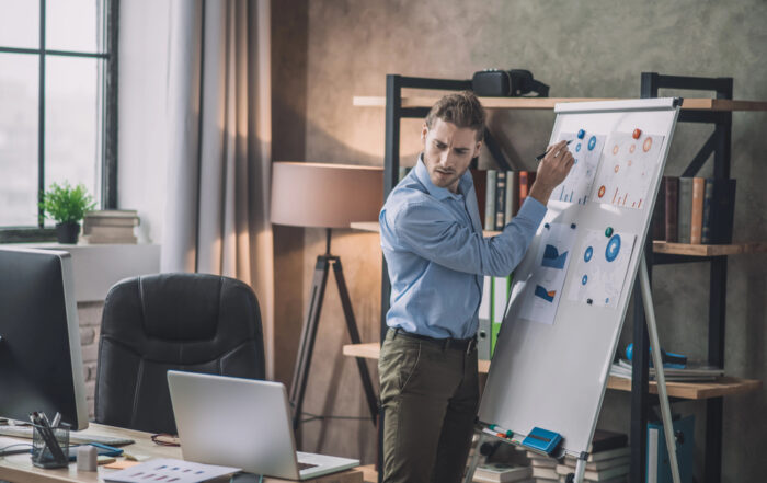 Barbat scriind pe whiteboard cu marker Pilot